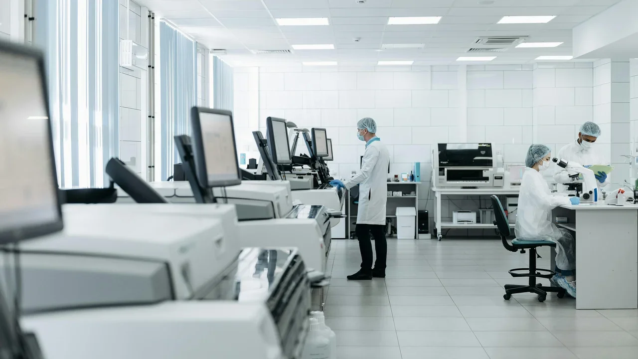Scientists working in a modern laboratory with large equipment and computer monitors.